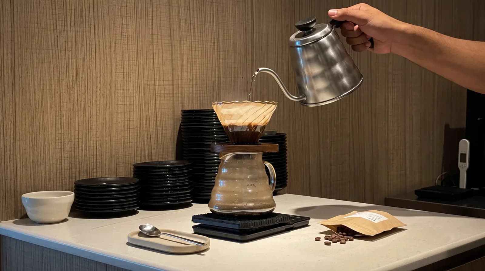45° shot: a full V60 slurry mid-swirl, gooseneck kettle exiting frame top-right.